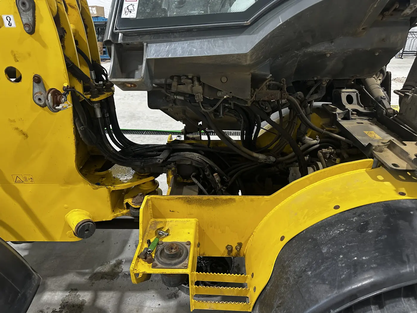 Wheel loader with its cab tilted to expose hydraulic hoses and hard lines