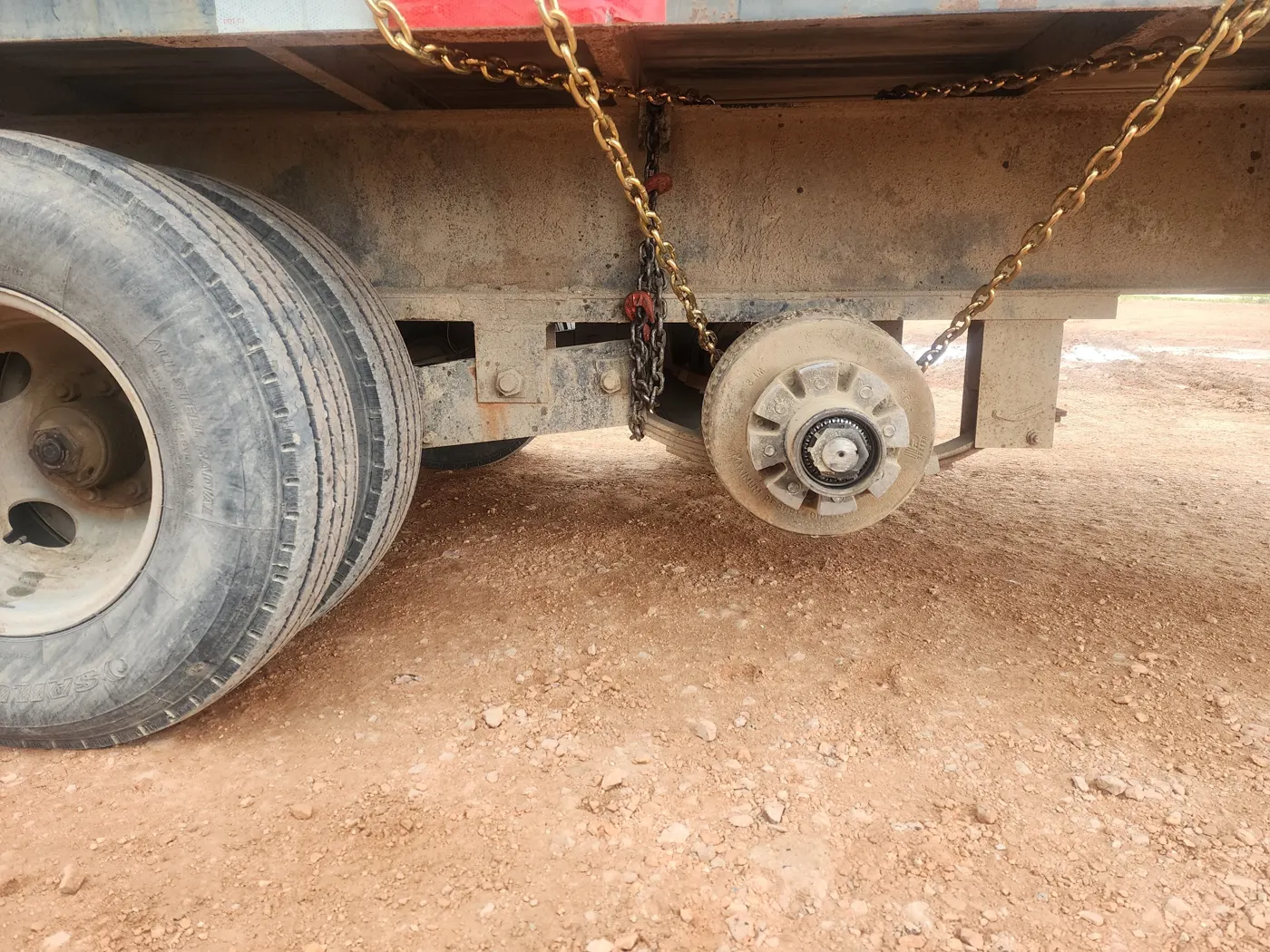 Flatbed trailer axle with the wheel removed exposing the hub